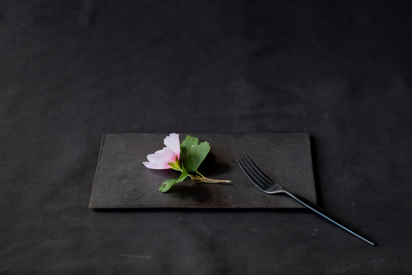 flower and black fork on black rectangular ceramic plate