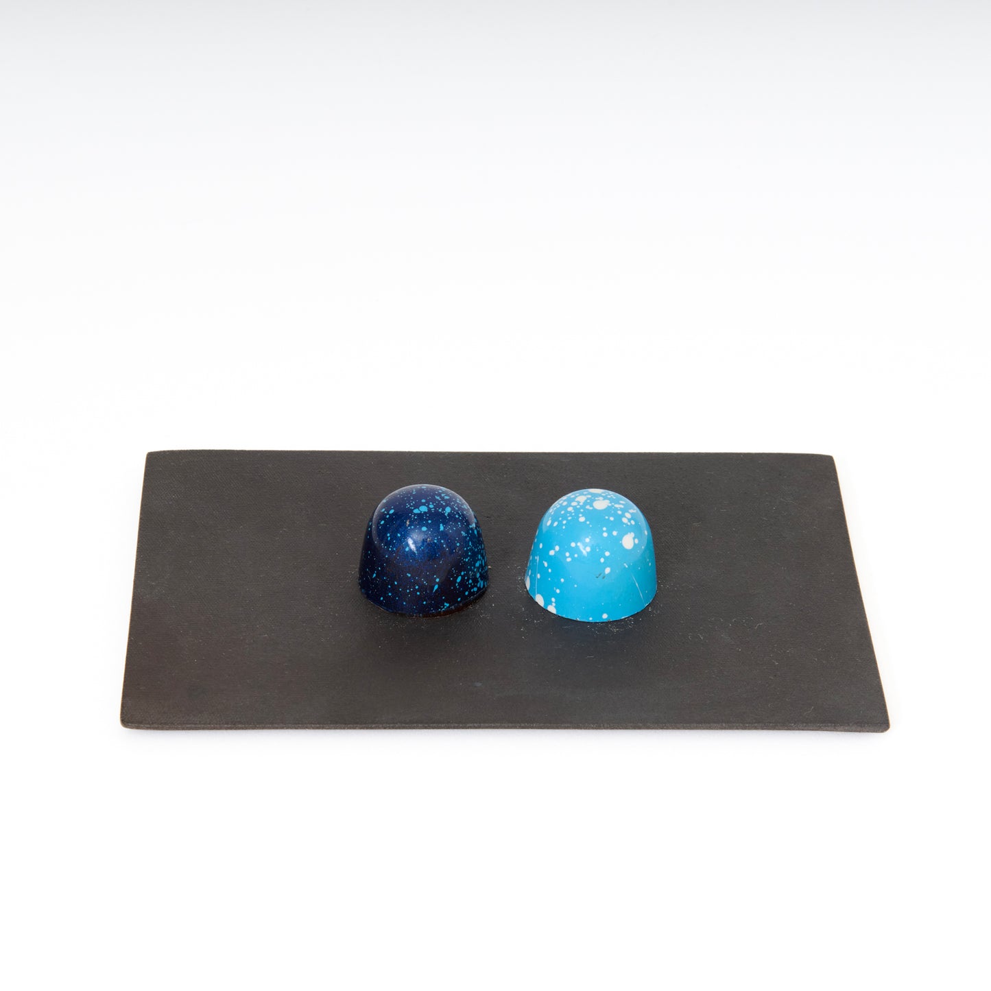 two blue chocolates on black rectangular slim ceramic plate