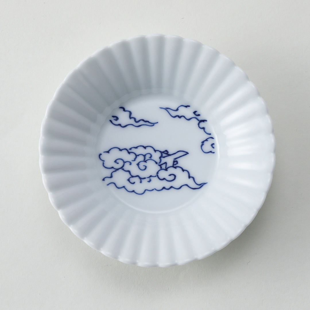 White ceramic fluted plate with blue cloud design on a light gray background