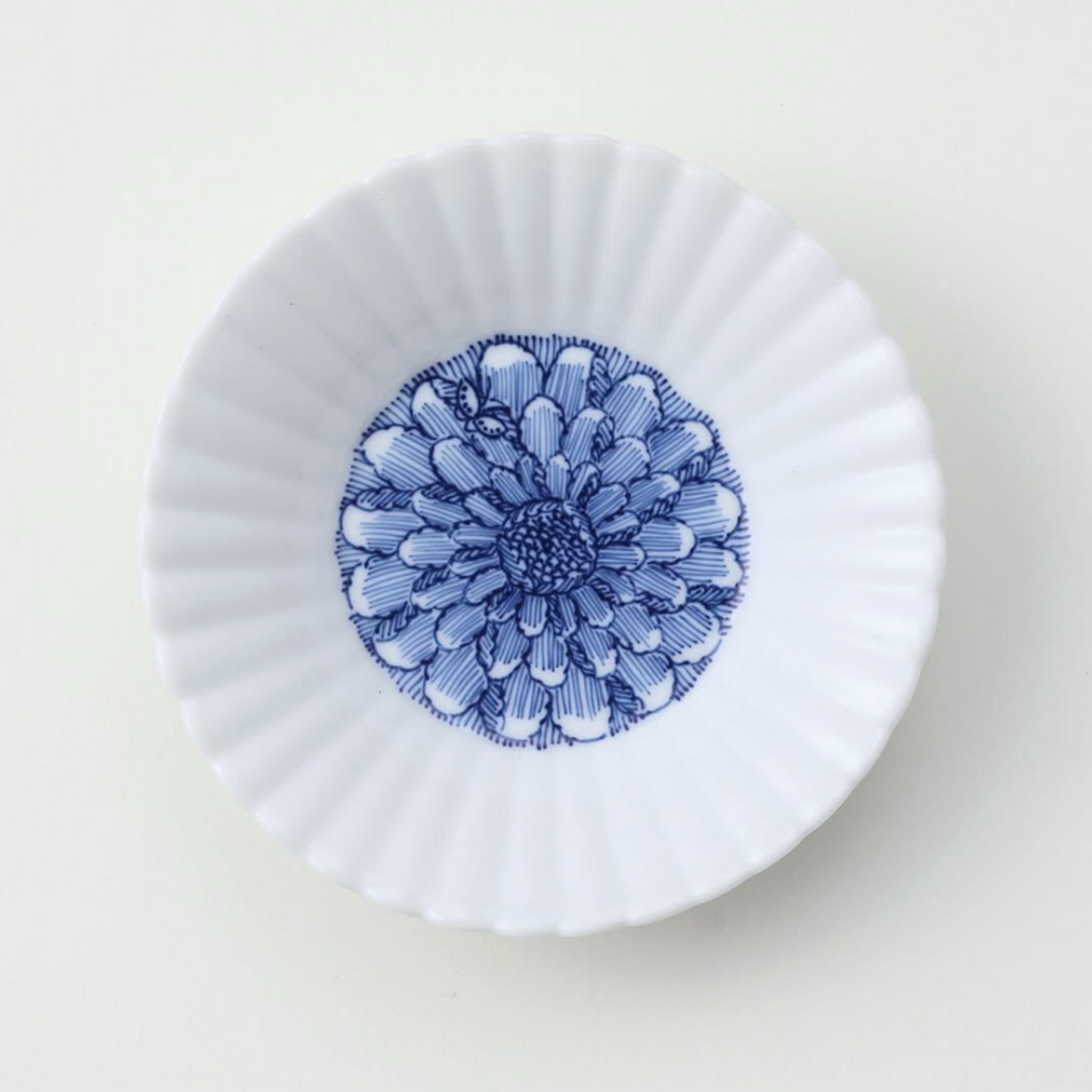 White ceramic fluted plate with blue peonies design on a light gray background