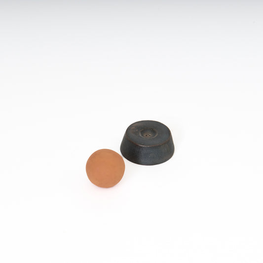 round terracotta ceramic sphere next to a black ceramic circular trapezoid base 