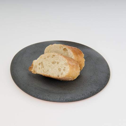 black round ceramic plate with two pieces of bread on top